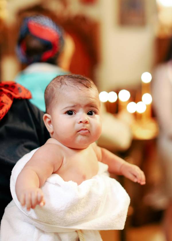 baby, wrapped in a towel at ceremony, making with a confused face
